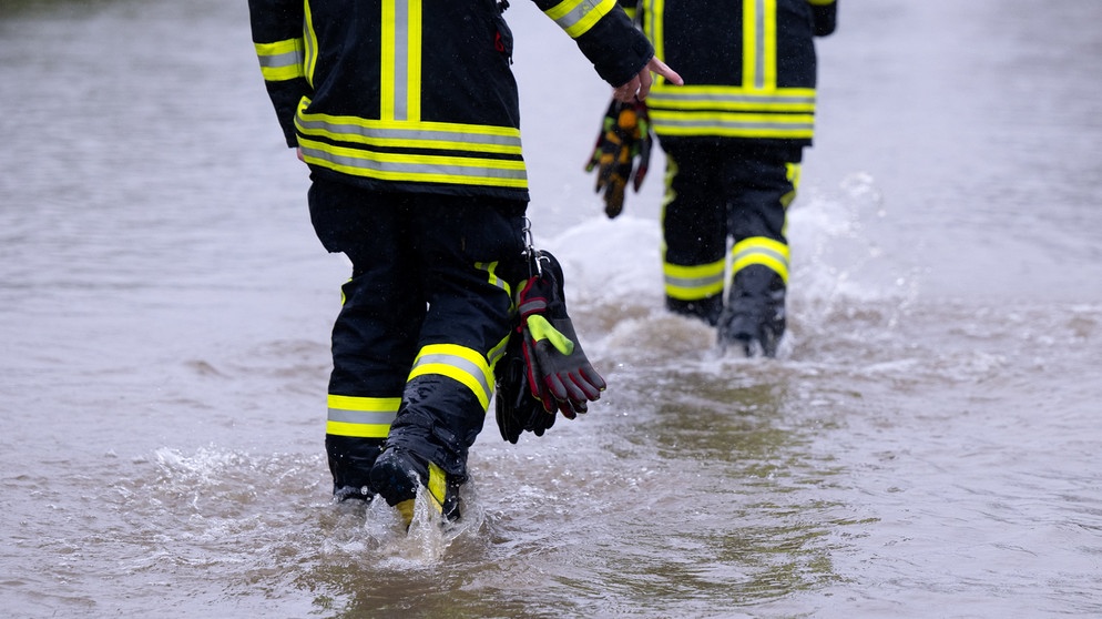 Unwetter in Bayern - Feuerwehrleute gehen über eine überflutet Straße in Dasing im schwäbischen Landkreis Aichach-Friedberg | Bild: dpa-Bildfunk/Sven Hoppe