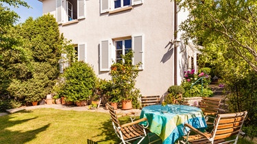 Garten mit Tisch vor einem Haus | Bild: mauritius images / Westend61 / Werner Dieterich