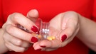 Frau schüttet Vitamin-Präparate in die Hand. | Bild: mauritius images