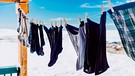 Vor schneebedeckter Kullisse hängt Wäsche an einer Wäscheleine. | Bild: mauritius images / NPSphotography / Alamy / Alamy Stock Photos