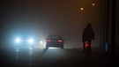 Ein Fahrradfahrer fährt am Morgen in zähem Nebel neben einer Straße. | Bild: dpa-Bildfunk/Sebastian Gollnow