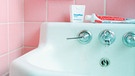 Zahnpasta vor Spiegel im bad mit rosa Fliesen | Bild: mauritius-images