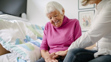 Eine Pflegerin hält die Hände einer Seniorin. | Bild: BR/Johanna Schlüter