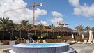 Hinter einem Hotel-Pool ist eine große Baustelle mit Kran zu sehen. | Bild: picture-alliance/dpa