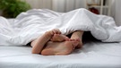 Die Füße zweier Menschen spitzen unter einer Bettdecke hervor | Bild: colourbox.com