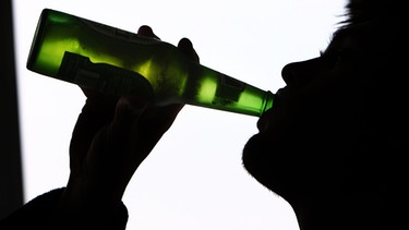 Symbolbild: Umrisse eines jungen Mannes, der aus einer grünen Bierflasche trinkt. | Bild: picture alliance / empics