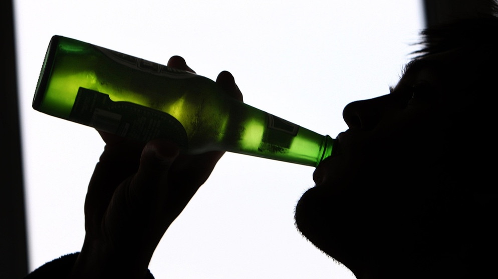 Symbolbild: Umrisse eines jungen Mannes, der aus einer grünen Bierflasche trinkt. | Bild: picture alliance / empics