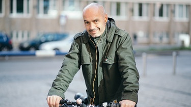 Bayern 2-Redakteur Michael Bartle hört einen Podcast beim Fahrradfahren. | Bild: BR