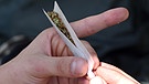 Cannabis in der Medizin: Man sieht die Hände eines jungen Mannes beim Drehen eines Joints. | Bild: picture-alliance/dpa