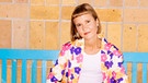 Die Autorin Caroline Wahl sitzt auf einer blauen Holzbank | Bild: Frederike Wetzels