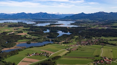 Luftaufnahme des Chiemsees und den umliegenden Seen mit den Chiemgauer Alpen im Hintergrund. | Bild: stock.adobe.com/mw-luftbildPhotografies