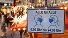 Schild mit der Aufschrift "Alle für Alle - 6:00 bis 24:00 Uhr", das auf die Maskenpflicht hinweist, vor Fußgängerzone mit Weihnachts-Deko | Bild: dpa-Bildfunk/Jan Woitas