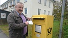 Martin Kreuzer wirft die letzte Postkarte der Fernschachgeschichte in seinen Briefkasten in Niederbayern. | Bild: BR/Thibaud Schremser