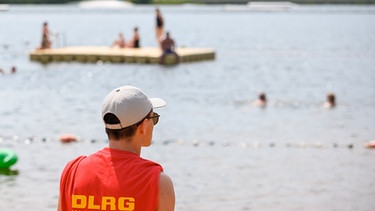 Ein Mitglied der DLRG (Deutsche Lebens-Rettungs-Gesellschaft) steht in einem Strandbad am Ufer | Bild: picture-alliance/dpa