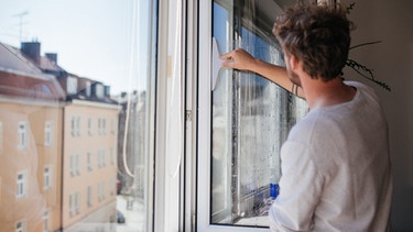 Ein Mann putzt seine Fenster. | Bild: BR/Julia Müller