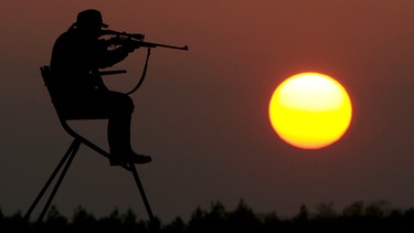 Archivbild: Jäger auf dem Hochsitz, im Hintergrund der Sonnenuntergang | Bild: picture-alliance/dpa