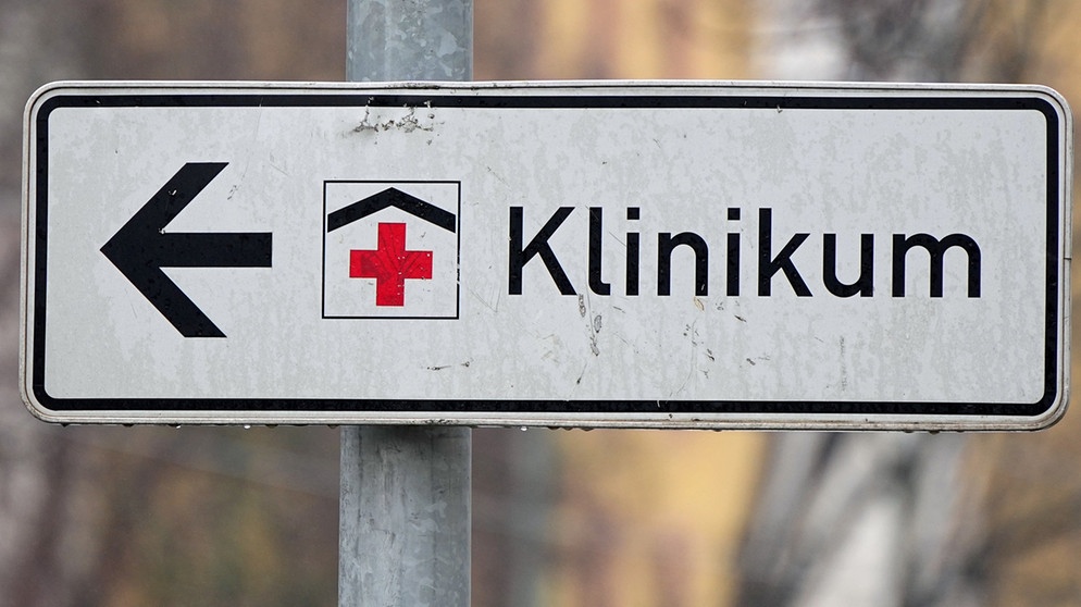 Ein Schild mit rotem Kreuz weist den Weg zu einem Klinikum. | Bild: dpa-Bildfunk/Soeren Stache