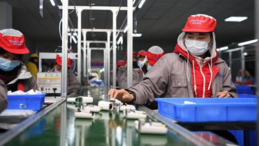 ARCHIV - 06.03.2020, China, Xiangtan: Menschen arbeiten in einer Fabrik am Fließband. // Symbolbild zur Diskussion um ein Gesetz zur Einhaltung von Menschenrechten und Umweltstandards in Lieferketten. | Bild: dpa-Bildfunk/Xue Yuge/XinHua/dpa