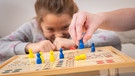Mensch ärgere dich nicht: Ein Kind bewegt eine Spielfigur auf einem Spielbrett (gestellte Szene). | Bild: picture-alliance/dpa/Benjamin Nolte