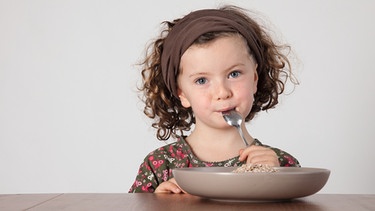 Kleines Mädchen sitzt am Tisch und isst Müsli. | Bild: Sonja Krebs / MEV