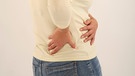 Eine Frau hält sich vor Schmerzen die Hände an die Niere. | Bild: picture-alliance/dpa
