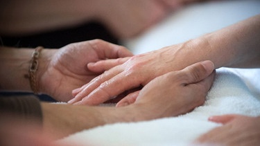 Berühren und Streicheln der Hände eines kranken Menschen | Bild: pa/dpa/Hans Wiedl