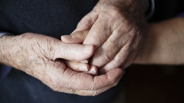 Senior hält die Hand einer Pflegerin. | Bild: Johanna Schlüter Fotografie/Johanna Schlüter