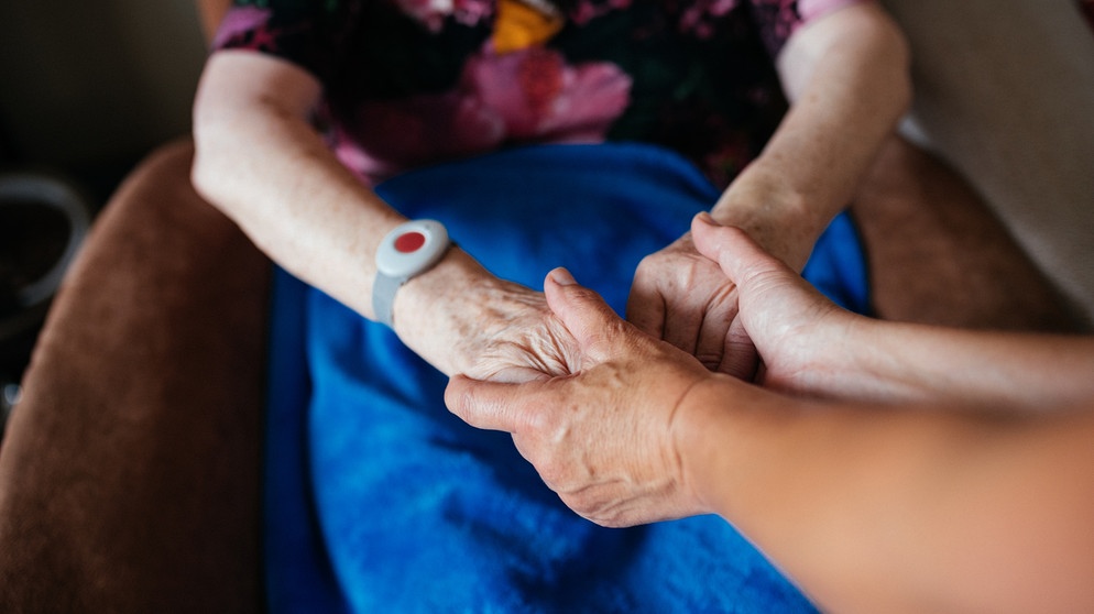 Symbolbild: Pflege zuhause: Eine junge Frau hält die Hände einer alten Frau. | Bild: BR/Julia Müller