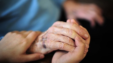 Eine Pflegekraft hält die Hand einer alten Frau | Bild: dpa-Bildfunk