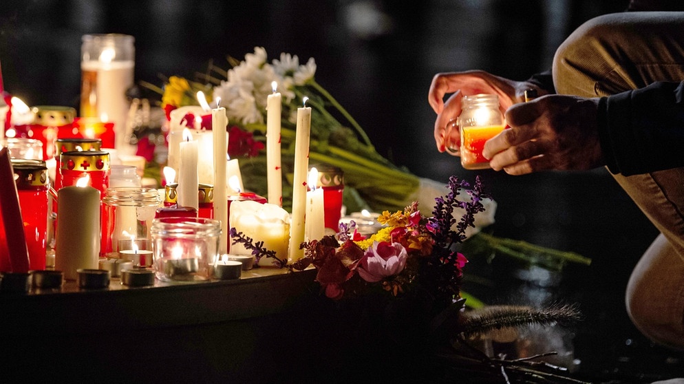 Ein Mann zündet eine Kerze auf dem Marktplatz an. Bei Schüssen in Halle sind zwei Menschen getötet worden.  | Bild: picture-alliance/dpa