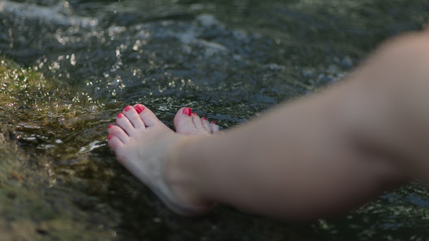 Eine Frau kühlt ihre Füße im Wasser. | Bild: BR
