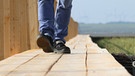 Ein Mann geht auf einem Holzsteg entlang. | Bild: picture-alliance.com