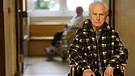 Älterer Mann sitzt im Rollstuhl und blickt dem Betrachter fest entgegen. | Bild: picture-alliance/dpa