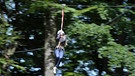 Eine Frau fährt eine Seilrutsche entlang im Waldklettergarten bei Kloster Banz | Bild: picture-alliance/dpa