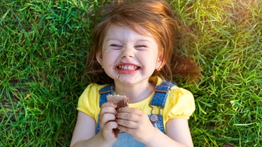 Kleines Mädchen isst lachend einen Schoko-Snack | Bild: colourbox.com