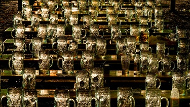 Hunderte von gläsernen Bierkrügen stehen nachts auf verlassenen Bierbänken eines geschlossenen Biergartens im Münchner Stadtteil Haidhausen. | Bild: picture-alliance/dpa/Peter Kneffel