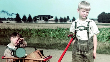 Junge mit Handwagen, in dem sein kleiner Bruder sitzt (1940) | Bild: picture-alliance/dpa/akg-images