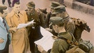 Nachkriegszeit 1945: Menschen schauen in eine Zeitung | Bild: picture alliance / akg-images | akg-images