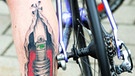 Teilnehmer eines Radrennens mit ungewöhnlicher Waden-Tätowierung | Bild: picture-alliance/dpa