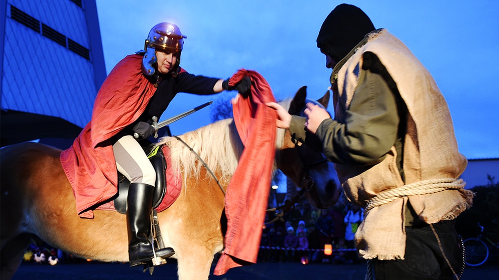 Eine als Sankt Martin verkleidete Reiterin teilt symbolisch ihren Mantel mit dem Schwert | Bild: picture-alliance/dpa