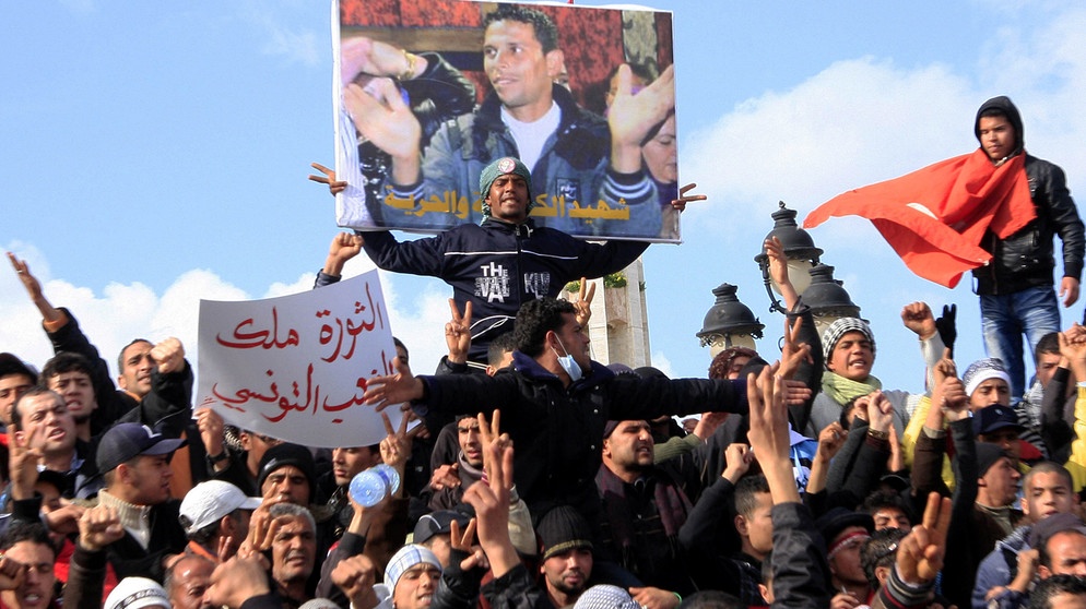 Wütende Demonstranten mit einem Bild "ihres" Märtyrers, des Gemüsehändlers Mohamed Bouazizi, im Januar 2011 in Tunis | Bild: picture alliance / ASSOCIATED PRESS | Salah Habibi