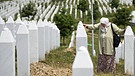 Das Hauptdenkmal und der Friedhof für den Genozid von Srebrenica in Potočari: Nura Mustafic trauert hier um ihre 3 Söhne und ihren Mann, sie berührt zwei Grabsteine, es sind die ihrer Söhne  | Bild: Imago