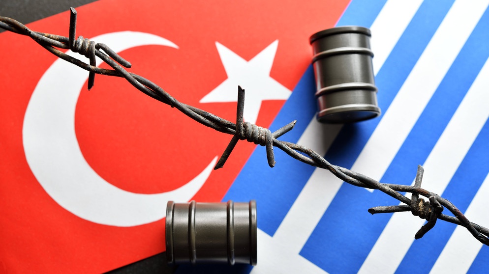 Symbolbild zum Konflikt um Öl- und Gasvorkommen im Mittelmeer: Stacheldraht und Ölfässer vor dem Hintergrund der türkischen und griechischen Flagge | Bild: imago images