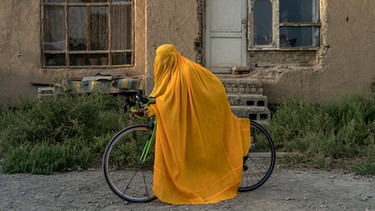 Eine mit gelber Burka verschleierte Frau in Kabul mit einem Fahrrad | Bild: dpa-Bildfunk/Ebrahim Noroozi