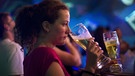 Das Nachtleben in Moskau. Im Club "Zona" trinkt eine Junge Frau ein Bier. Im Hintergrund junge Menschen, die rumstehen, trinken und tanzen. | Bild:  ITAR-TASS / dpa / Bobylev Sergei