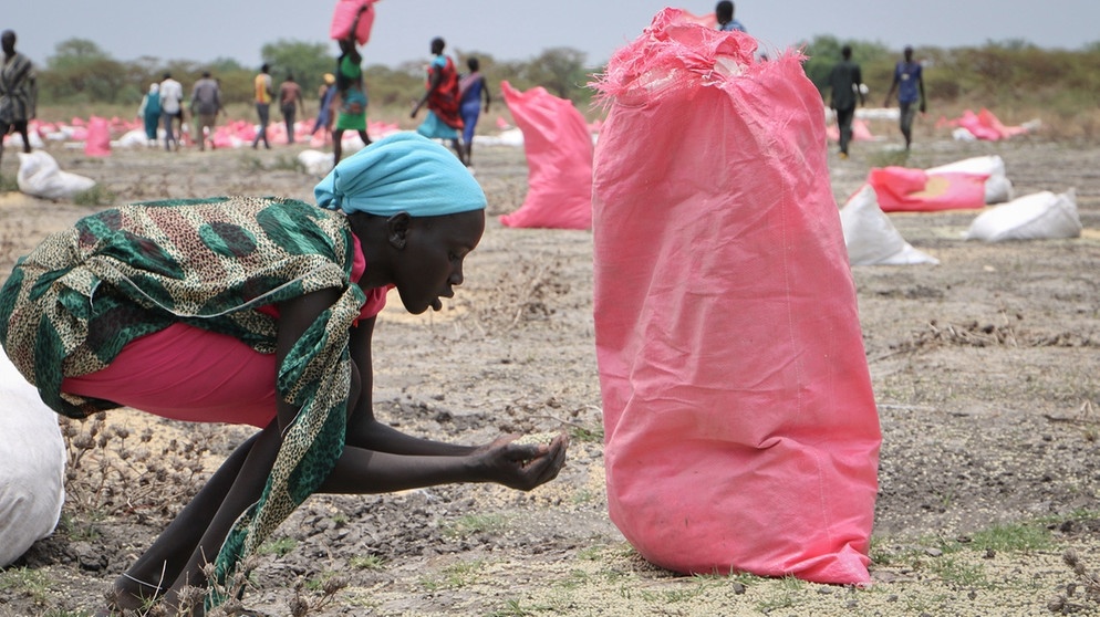 Südsudan, Kandak: Eine Frau sammelt im Jahr 2018 Hirse vom Boden auf, die in Säcken vom Welternährungsprogramm der Vereinten Nationen abgeworfen wurden, um einer Hungerskrise entgegenzuwirken. | Bild: dpa-Bildfunk/Sam Mednick