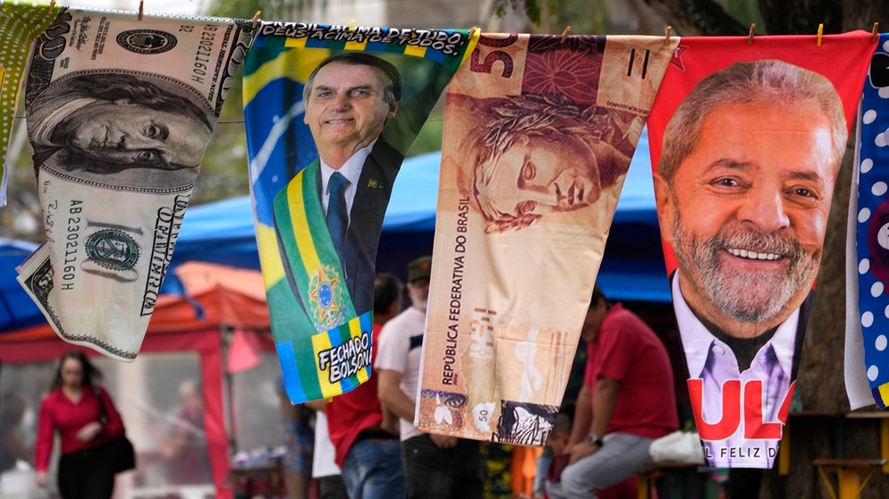 Handtücher mit Porträts der brasilianischen Präsidentschaftskandidaten Bolsonaro und Lula sowie mit Bildern von Geldscheinen werden in Brasilia von einem Straßenhändler auf einer Wäscheleine zum Verkauf angeboten | Bild: dpa-Bildfunk/Eraldo Peres