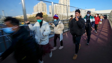 Pendler mit Maske gehen über eine Fußgängerbrücke in Peking, ein Mann ohne Maske raucht | Bild: dpa-Bildfunk/Andy Wong