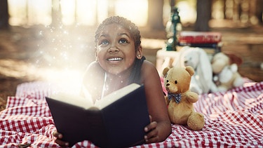 Erlösende Kraft der Märchen - Symbolbild (Mädchen liest in Märchenbuch und freut sich)  | Bild: colourbox.com