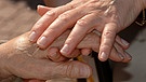 Eine Betreuerin streichelt während des "Betreuten Urlaubs" für Alzheimerkranke einer Patientin die Hand. | Bild: picture-alliance/dpa